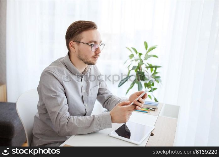 business, startup and people concept - businessman or creative male worker texting on smarphone at home office
