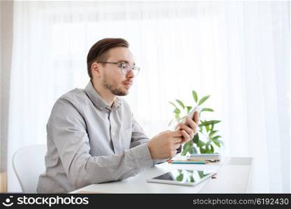 business, startup and people concept - businessman or creative male worker texting on smarphone at home office