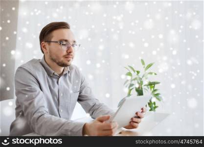 business, startup and people concept - businessman or creative male worker with tablet pc computer at home office over snow