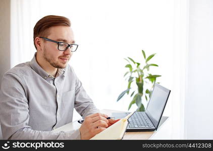 business, startup and people concept - businessman or creative male worker writing to notebook or diary with pen at home office