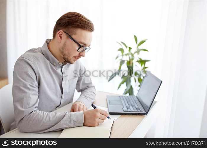 business, startup and people concept - businessman or creative male worker writing to notebook or diary with pen at home office