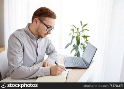 business, startup and people concept - businessman or creative male worker writing to notebook or diary with pen at home office