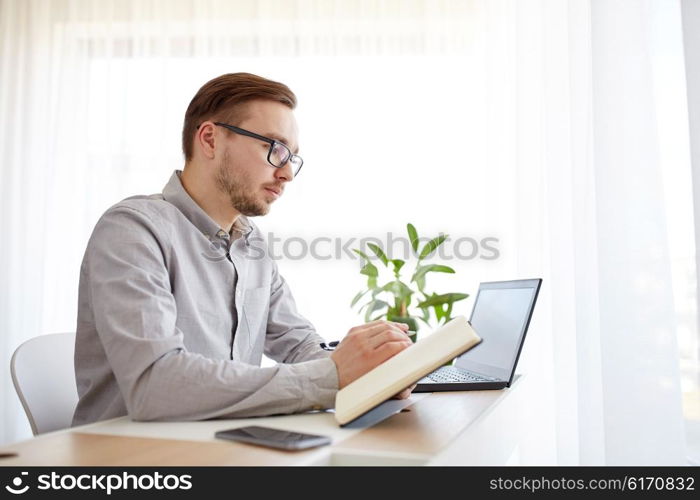 business, startup and people concept - businessman or creative male worker writing to notebook or diary with pen at home office