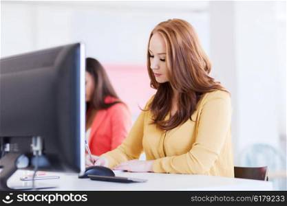 business, startup and people concept - businesswoman or creative female office worker with computer writing to notebook