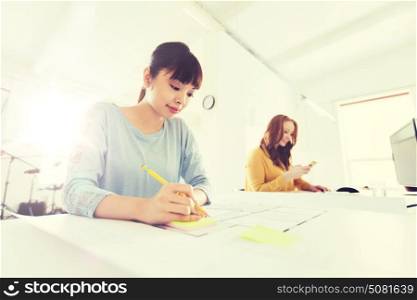 business, startup and people concept - creative or architect woman with blueprint writing on sticker at office. architect woman with blueprint writing at office