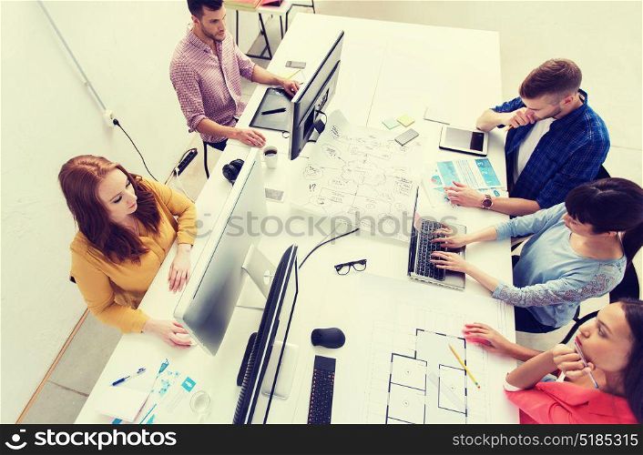business, startup and people concept - creative team with computers, blueprint and scheme at office. creative team with computers, blueprint at office