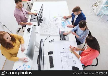 business, startup and people concept - creative team with computers, blueprint and scheme at office