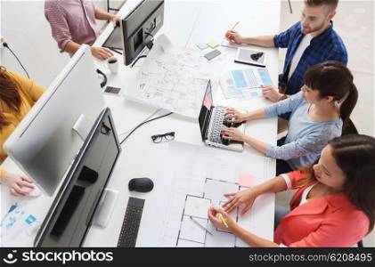 business, startup and people concept - creative team with computers, blueprint and scheme at office