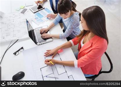 business, startup and people concept - creative team with laptop and blueprint at office