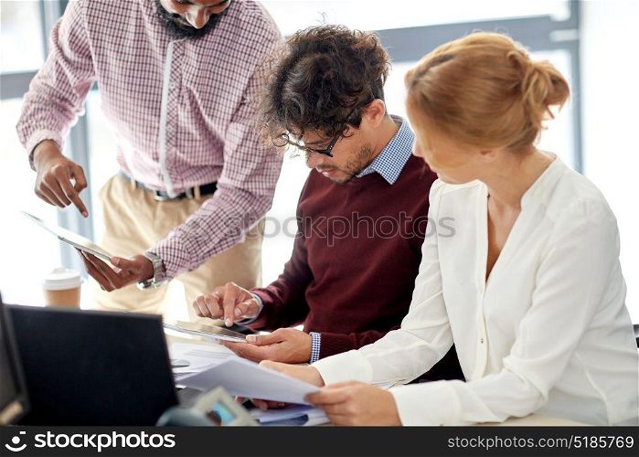 business, startup and people concept - creative team with papers and tablet pc computer in office. business team with tablet pc in office