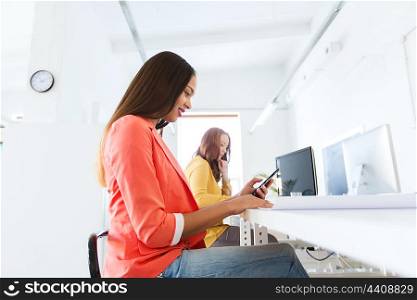 business, startup and people concept - happy african american businesswoman or creative worker texting on smartphone at office