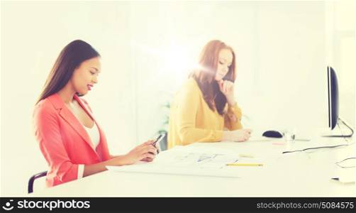 business, startup and people concept - happy african american businesswoman or creative worker texting on smartphone at office. businesswoman texting on smartphone at office. businesswoman texting on smartphone at office
