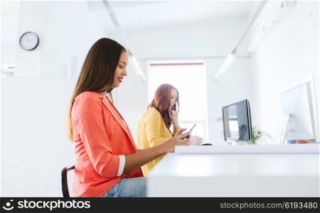 business, startup and people concept - happy african american businesswoman or creative worker texting on smartphone at office