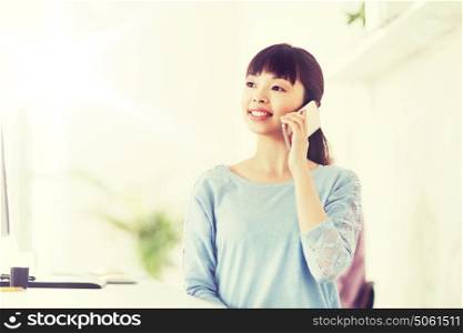 business, startup and people concept - happy asian businesswoman or creative worker calling on smartphone at office. businesswoman calling on smartphone at office