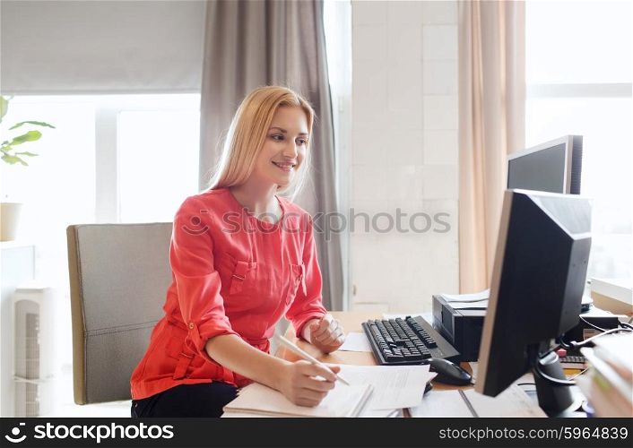 business, startup and people concept - happy businesswoman or creative female office worker with computers writing to notebook