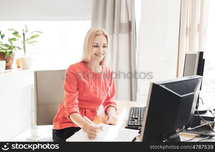 business, startup and people concept - happy businesswoman or creative woman with computers writing to notebook at office