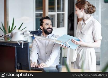 business, startup and people concept - happy creative team with computer and files in office