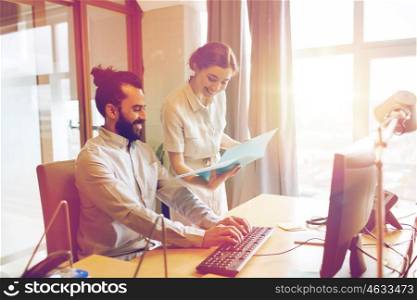 business, startup and people concept - happy creative team with computer and folder in office
