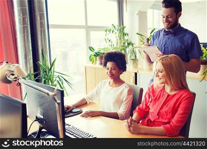 business, startup and people concept - happy creative team with computer and notebook in office