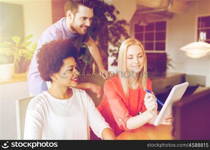 business, startup and people concept - happy creative team with computer and notebook in office