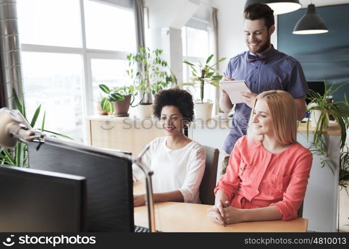 business, startup and people concept - happy creative team with computer and notebook in office