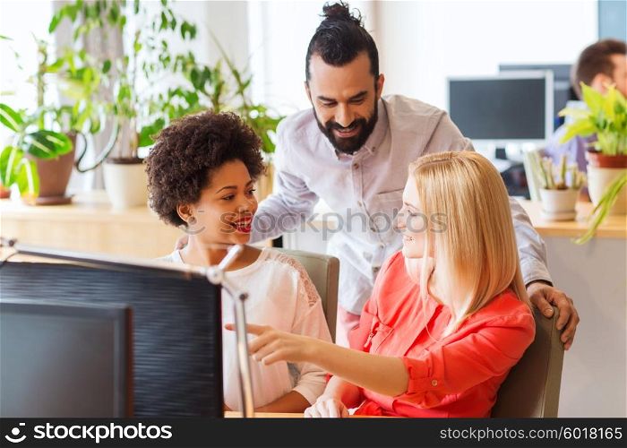 business, startup and people concept - happy creative team with computer discussing something in office