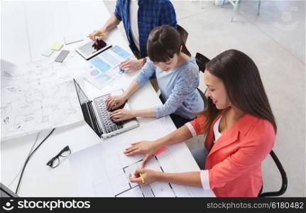 business, startup and people concept - happy creative team with laptop and blueprint at office