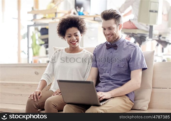 business, startup and people concept - happy creative team with laptop computer and folder in office