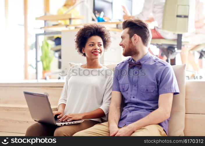 business, startup and people concept - happy creative team with laptop computer and folder in office