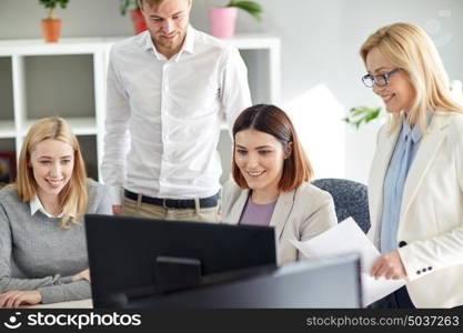 business, startup and people concept - happy creative team with papers and computer in office. happy business team with computer in office