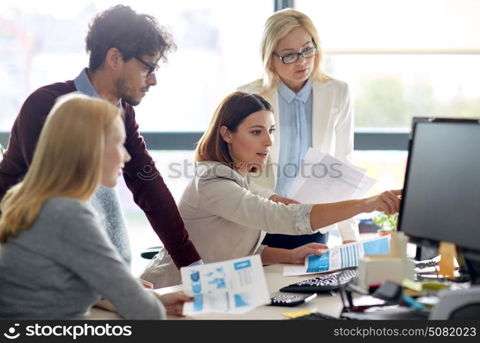 business, startup and people concept - happy creative team with papers and computer in office. happy business team with computer in office