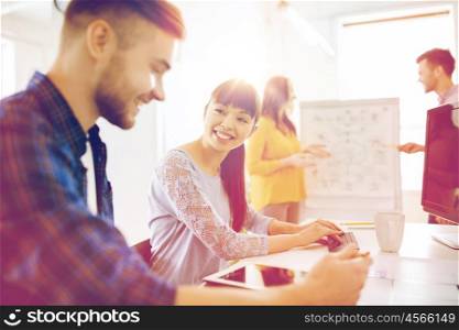 business, startup and people concept - happy creative team with tablet pc computer at office