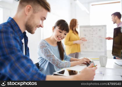business, startup and people concept - happy creative team with tablet pc computer at office