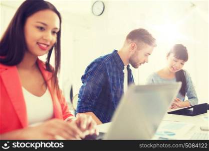 business, startup and people concept - happy international creative team with tablet pc and papers at office. creative team with tablet pc and papers at office. creative team with tablet pc and papers at office