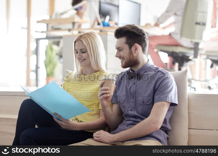 business, startup and people concept - happy man and woman with folder drinking coffee in office
