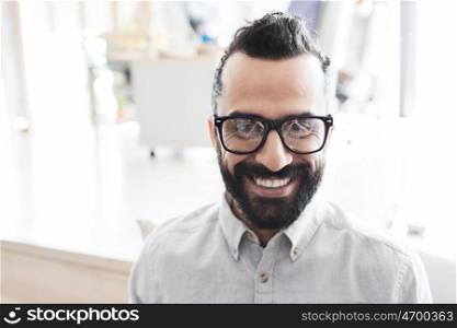 business, startup, and people concept - happy smiling latin man with eyeglasses and beard at office