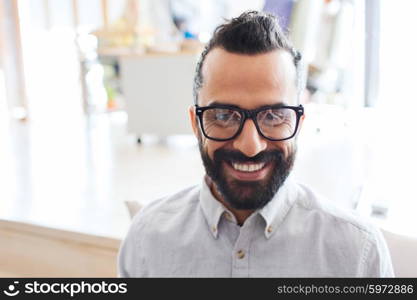 business, startup, and people concept - happy smiling latin man with eyeglasses and beard at office