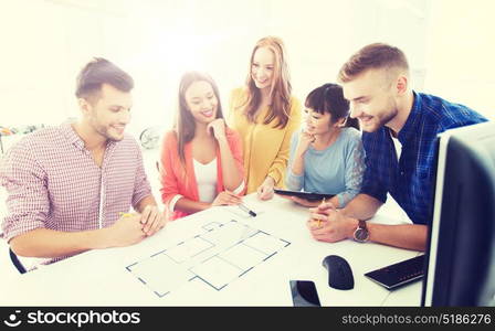 business, startup, architecture and people concept - happy international creative architect team or students with blueprint working at office. creative team with blueprint working at office