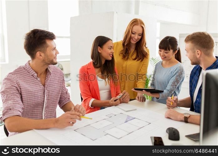 business, startup, architecture and people concept - happy international creative architect team or students with blueprint and tablet pc computer working at office. creative team with blueprint working at office. creative team with blueprint working at office