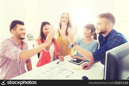 business, startup, architecture, gesture and people concept - happy international creative architect team or students with blueprint making high five at office. creative team making high five at office