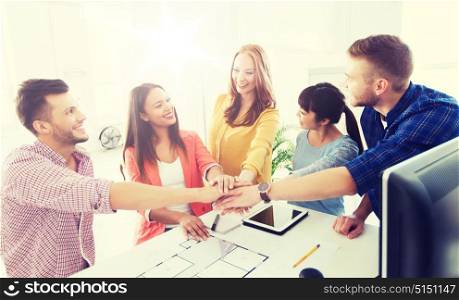 business, startup, architecture, gesture and people concept - happy international creative architect team or students with blueprint putting hands on top together at office. creative team holding hands together at office