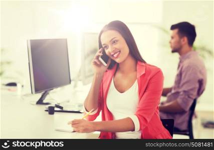business, startup, communication and people concept - happy african american businesswoman or creative worker calling on smartphone at office. businesswoman calling on smartphone at office