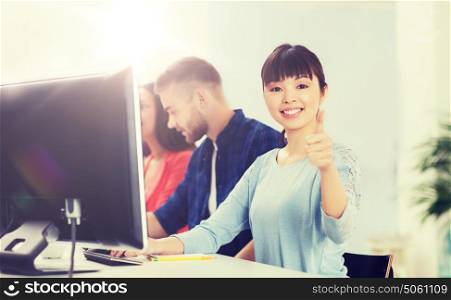 business, startup, education and people concept - happy young asian woman with pc computer over creative team or students working at office. happy creative team or students working at office