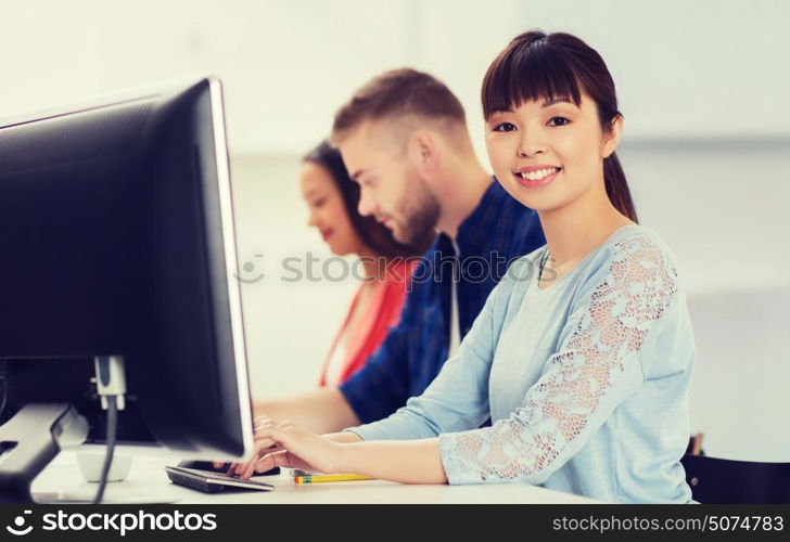 business, startup, education and people concept - happy young asian woman with pc computer over creative team or students working at office. happy creative team or students working at office