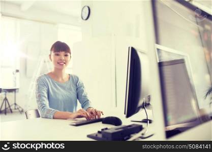business, startup, education and people concept - happy young asian woman with computer working at office. happy asian woman with computer at office. happy asian woman with computer at office