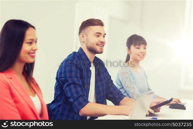 business, startup, education and people concept - happy young man over creative team or students working at office. happy creative team or students working at office
