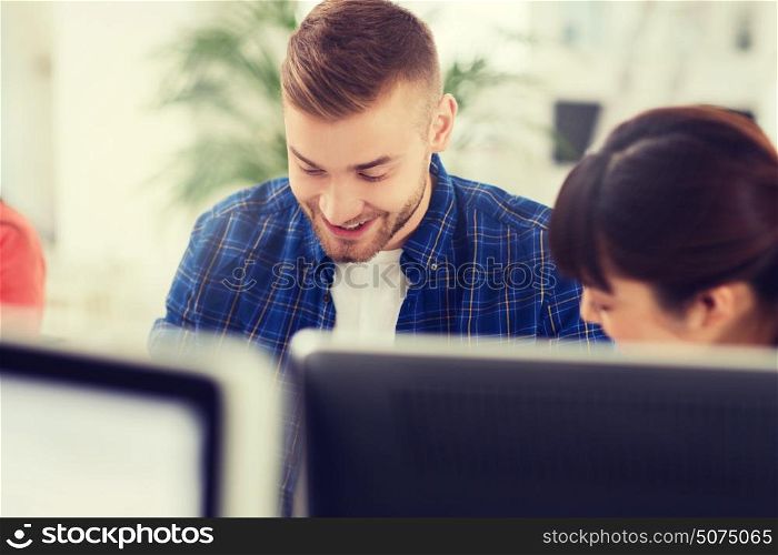 business, startup, education and people concept - happy young man with creative team or students working at office. happy creative team or students working at office