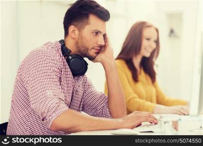 business, startup, education, technology and people concept - creative team or students with headphones and computer at office. creative team with headphones and computer