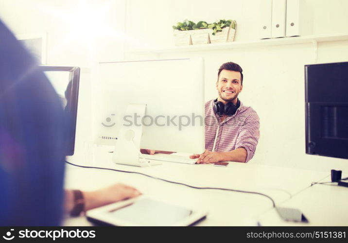 business, startup, education, technology and people concept - happy creative man or student with headphones and computer at office. creative man with headphones and computer