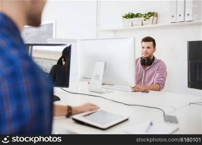 business, startup, education, technology and people concept - happy creative man or student with headphones and computer at office